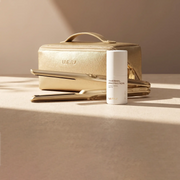 Hair care set featuring a wireless hair straightener, thermal protection spray, and stylish gold carrying case.