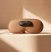 ELAX 2.0 relaxing eye mask displayed on a smooth surface, featuring a sleek design and control button.